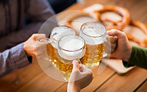 Close up of hands with beer mugs at bar or pub