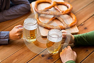 Close up of hands with beer mugs at bar or pub