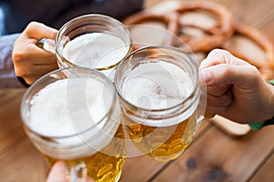 Close up of hands with beer mugs at bar or pub