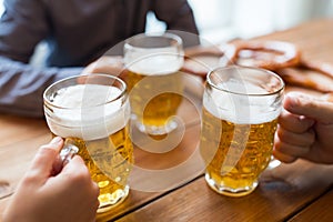 Close up of hands with beer mugs at bar or pub