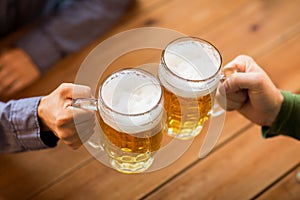 Close up of hands with beer mugs at bar or pub