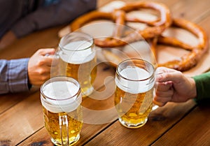 Close up of hands with beer mugs at bar or pub