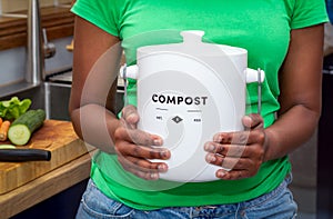 Close up of hands of black African Australian woman holding a kitchen compost container in kitchen