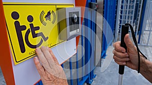 Close-up of the hands of a blind elderly woman reading a text in braille. Button for calling help for people with