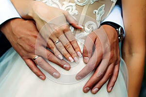 Close-up hands of bride and groom with wedding rings, newlyweds embracing. Concept of love, wedding and family