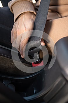 close-up of the hands buckling the seat belt in the car