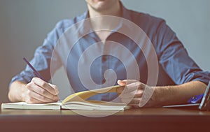 Pohled zblízka na ruky z podnikatel v modrý košile podpisu nebo na list z zápisník 