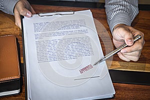 Close up hands of businessman pointing to signing and stamp on paper document to approve business investment contract agreement