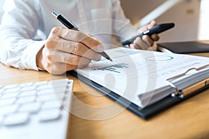 Close-up of hands Businessman reading and writing with pen signing contract over document for Completing Application Form at work