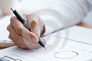 Close-up of hands Businessman reading and writing with pen signing contract over document for Completing Application Form at work