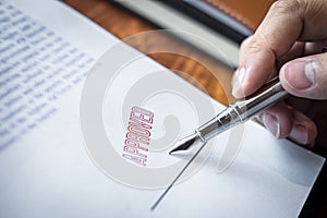 Close up hands of businessman signing and stamp on paper document to approve business investment contract agreement
