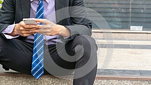 Close up hands businessman uses smartphone sitting at walkway pedestrian
