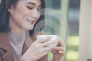 Close up Hands of businesswoman love drinking hot coffee. Woman hand holding black coffee cup in green garden cafe. business women