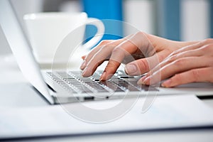 Close-up of hands of businesswoman typing on a laptop