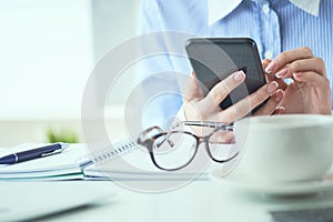 Close up of hands of businesswoman using smartphone at office. Business, technology and people concept.