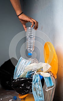 Close up hands of Careless negligible people throwing single use plastic water bottle into the filled trash can or garbage bin