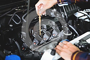 Close up hands checking lube oil level of car engine from deep-stick for service and maintenance concept