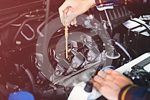 Close up hands checking lube oil level of car engine from deep-stick for service and maintenance concept vintage tone