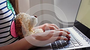 Close-up of hands, child is typing on a laptop keyboard, inside an airplane, sitting by an illuminator, holding a small