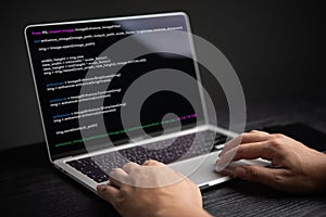 Close-up of hands coding on laptop, displaying programming interface. Represents software development, technology. Suitable for IT