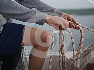 Close up of hands coiling up a rope, the halyard