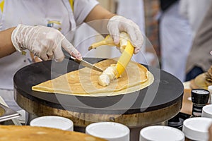 Close-up of hands of cook in gloves preparing Crepe, pancake with fresh banana. Healthy fresh food. Concept national