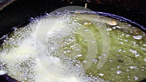 Close-up of the hands of the cook putting the dough into the boiling oil in the frying pan