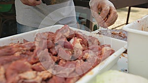 Close-up of the hands of the cook who cuts pieces of pickled meat on the board