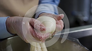 Close up for hands in cooking gloves preparing mozzarella cheese, food concept. Frame. Worker from cheese factory