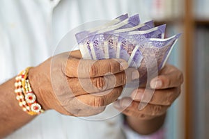 Close up hands Counting Indian Currency notes at cloth shop - Concept of back to business, profit, making money and