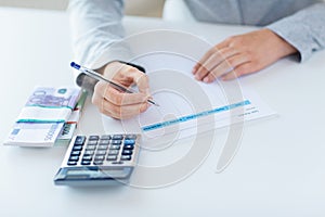 Close up of hands counting money with calculator