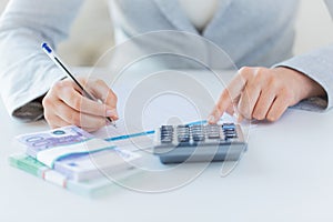 Close up of hands counting money with calculator