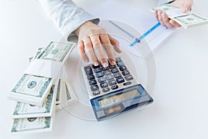 Close up of hands counting money with calculator