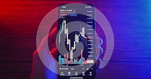 Close up hands of crypto trader holding mobile phone analyzes cryptocurrency price. Crypto investor makes money using