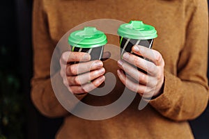 Close-up of hands with cups of coffee. Girl bought takeaway coffee. Beautiful  fragrant  freshly brewed cappuccino with a