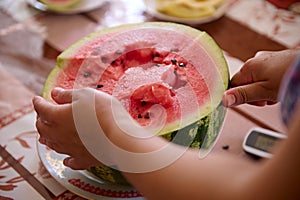 Close-up hands cutting a slice of ripe organic juicy watermelon.