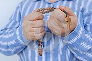 close-up hands, elderly believing woman, Christian living in world with wooden rosary in hands, use rosary when praying, religious