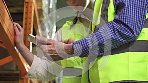 Close-up of the hands of an elderly manager and a young employee with a computer tablet in a vest working in the