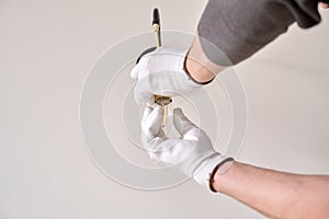 Close-up hands of electrician installing wall lamp