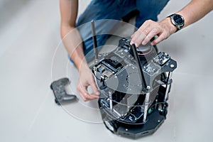 Close up hands of engineer or technician worker check and maintenance small robotic machine that put on the floor beside