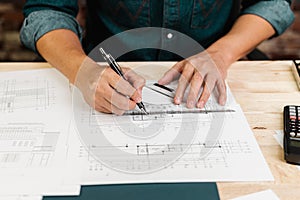 Close up hands of an engineer working and sketching on blueprints. Engineer planning project on paperwork with equipment