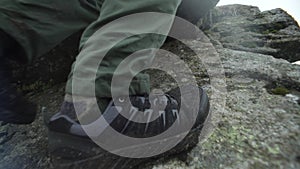 Close-up of the hands and feet of a man climbing a mountain on rocks.