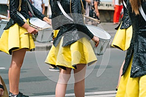 Close-up of hands of female drummers in yellow black vintage uniform at parade