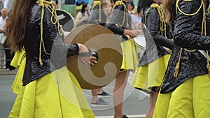 Close-up of hands of female drummers in yellow black vintage uniform at parade. Street performance. Parade of majorettes