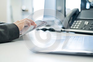 Close-up of the hands of a female secretary with a digital tablet. Faceless woman at her desk in the office.