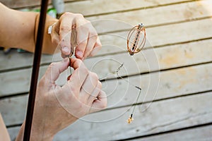 Close-up of the hands of a fisherman who impales worms on the hook of a fishing rod photo