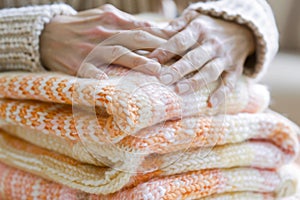 Close-up of hands folding cozy knitted sweaters