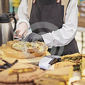 Close-up of hands of girl in black apron cutting craft pie. Fresh organic vegan food concept, recipes and cooking