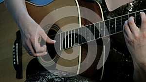 Close-up of the hands of a girl playing an acoustic guitar. Focus on the fingers clamping the chords on the fretboard. Day of musi