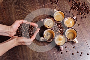 Close-up of the hands of a girl who sprinkles roasted coffee beans to the floor. On the floor there are cups of freshly brewed